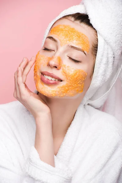 Happy girl with citrus facial mask touching face with closed eyes isolated on pink — Stock Photo