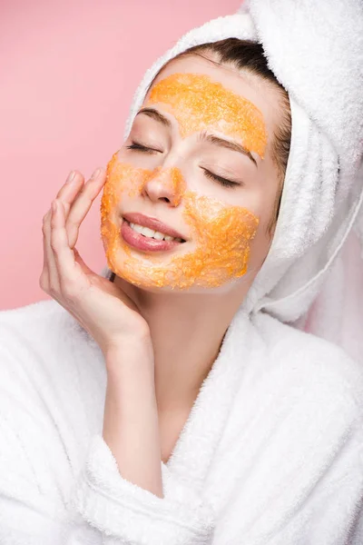 Menina feliz com máscara facial cítrica tocando rosto com olhos fechados isolados em rosa — Fotografia de Stock