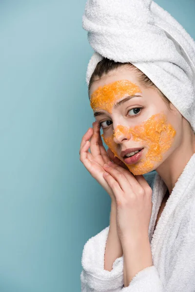 Dreamy girl with citrus facial mask touching face on blue background — Stock Photo