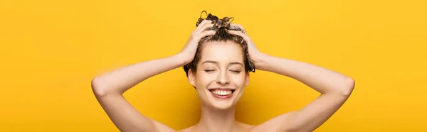 Panoramic shot of girl with closed eyes washing hair on yellow background — Stock Photo