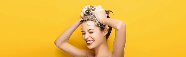 Tiro panorâmico de menina feliz com os olhos fechados lavar o cabelo no fundo amarelo — Fotografia de Stock