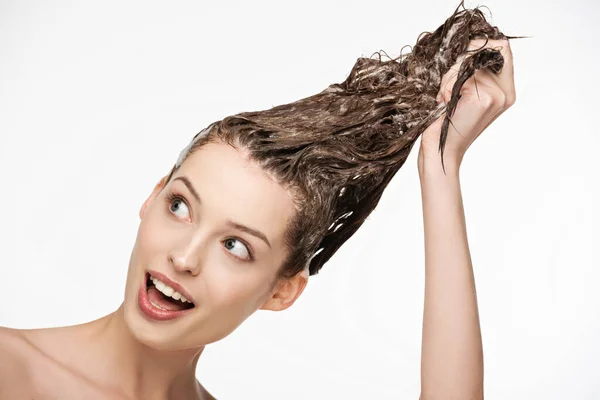 Excited young woman with open mouth washing long hair isolated on white — Stock Photo