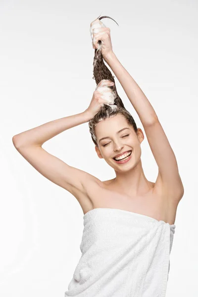 Joyeuse jeune femme laver les cheveux longs avec les yeux fermés isolé sur blanc — Photo de stock