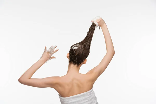 Вид ззаду молодої жінки, що миє довге волосся ізольовано на білому — стокове фото