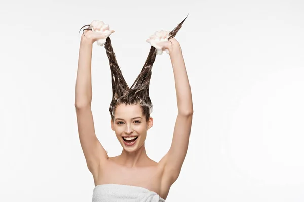 Cheerful girl having fun while washing long hair isolated on white — Stock Photo