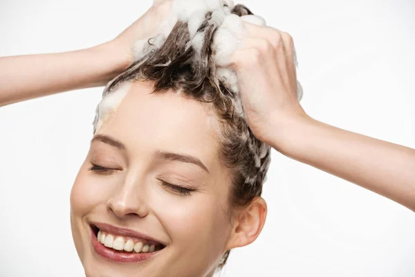 Happy girl with closed eyes washing hair isolated on white — Stock Photo