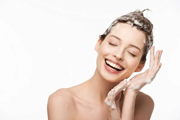 Chica alegre con el pelo jabonoso y los ojos cerrados sonriendo aislado en blanco - foto de stock