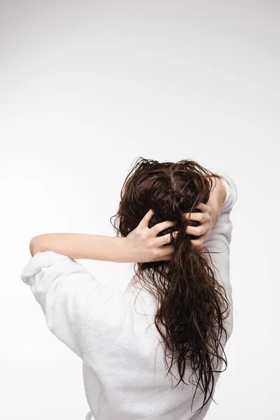 Вид сзади молодой женщины, касающейся мокрых чистых волос, изолированных на белом — стоковое фото