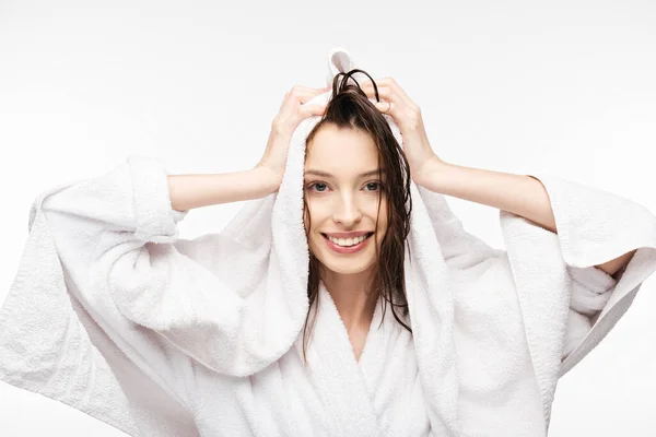 Happy girl wiping wet clean hair with white terry towel while smiling at camera isolated on white — Stock Photo