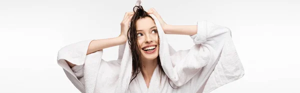 Plano panorámico de chica feliz limpiando el cabello limpio húmedo con toalla de rizo blanco mientras mira hacia otro lado aislado en blanco - foto de stock