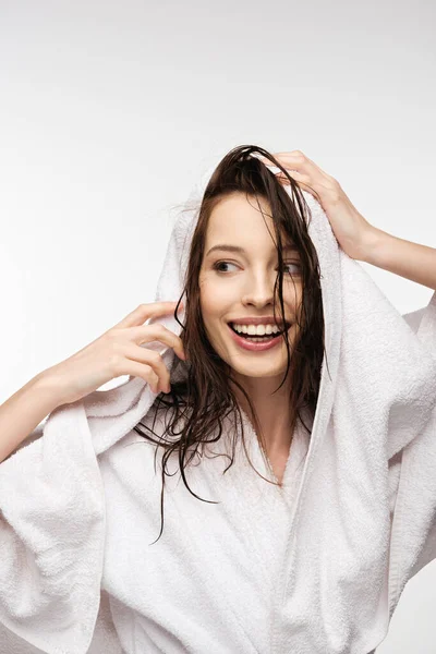 Fröhliches Mädchen wischt nasses, sauberes Haar mit weißem Handtuch ab, während es isoliert auf weißem Grund wegschaut — Stockfoto