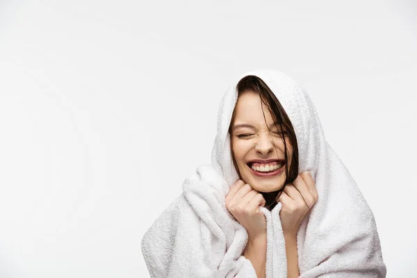 Menina animado, envolto em toalha, sorrindo com os olhos fechados isolados no branco — Fotografia de Stock