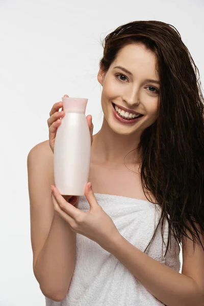 Menina feliz olhando para a câmera enquanto segurando garrafa de xampu isolado no branco — Fotografia de Stock