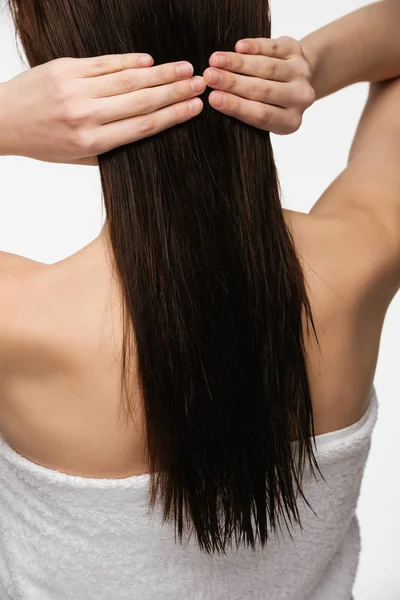 Vista posteriore della giovane donna bruna che tocca i capelli lunghi puliti isolati sul bianco — Foto stock