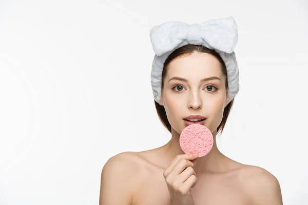 Menina bonita segurando esponja cosmética perto de lábios enquanto olha para a câmera isolada no branco — Fotografia de Stock