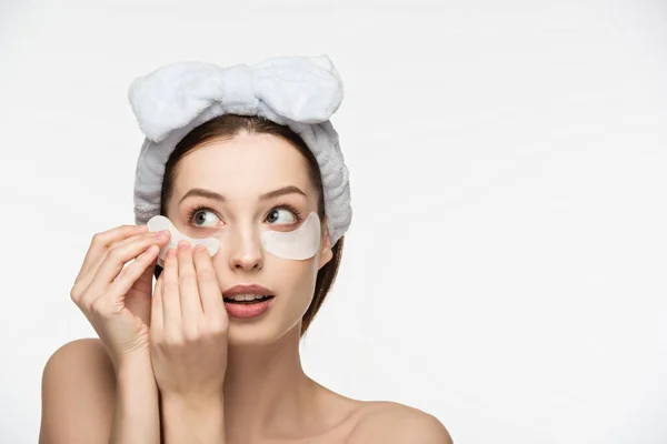 Hermosa mujer joven aplicando parche ocular aislado en blanco - foto de stock