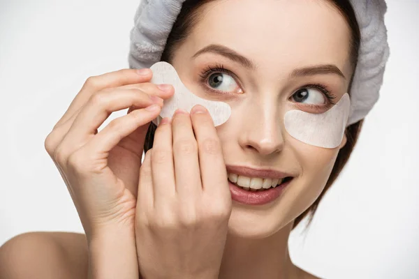 Hermosa, chica sonriente aplicando parche para los ojos aislado en blanco - foto de stock