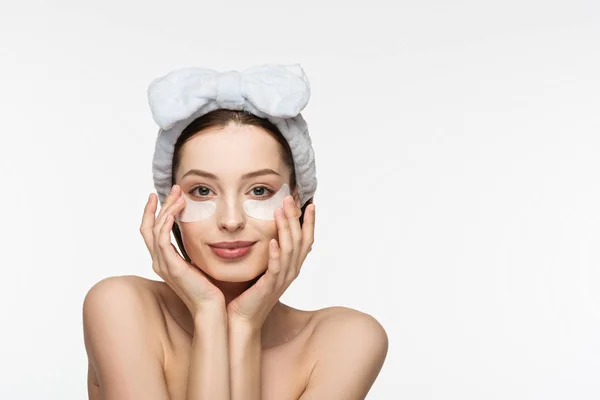 Chica feliz con parches en los ojos tocando la cara mientras mira a la cámara aislada en blanco - foto de stock