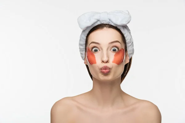 Jolie fille avec les yeux grands ouverts, visage de canard et des taches de collagène sur le visage en regardant la caméra isolée sur blanc — Photo de stock