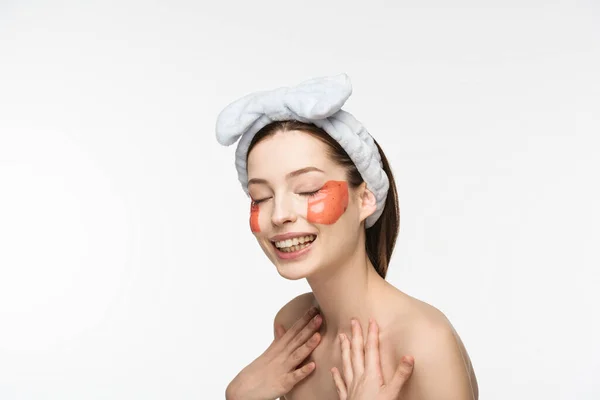 Chica sonriente con parches de colágeno en forma de labio tocando el pecho aislado en blanco - foto de stock