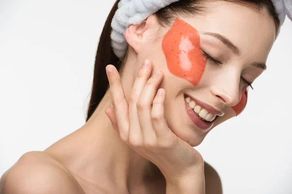 Chica feliz con los ojos cerrados tocando la cara con parche de colágeno en forma de labio aislado en blanco - foto de stock