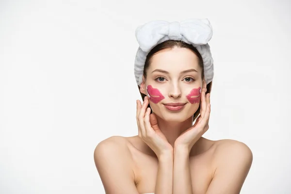 Atractiva chica sonriente con parches de colágeno en forma de labio tocando la cara y mirando a la cámara aislada en blanco - foto de stock