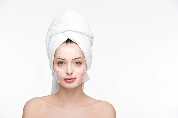 Привлекательная девушка в пилинговой маске на лице и полотенце на голове, смотрящая на камеру, изолированную на белом — стоковое фото