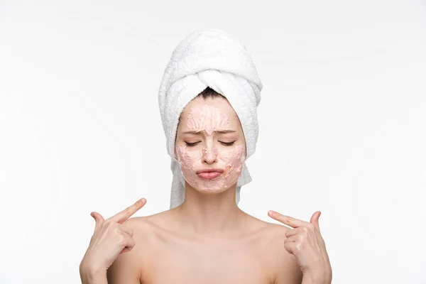 Disgustado apuntando con los dedos a la mascarilla peladora en la cara mientras está de pie con los ojos cerrados aislados en blanco - foto de stock