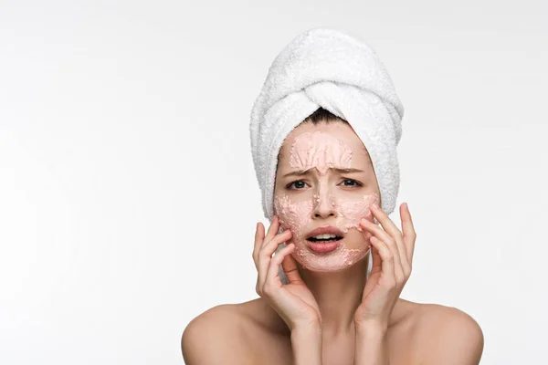 Displeased girl with facial peeling mask touching face while looking at camera isolated on white — Stock Photo