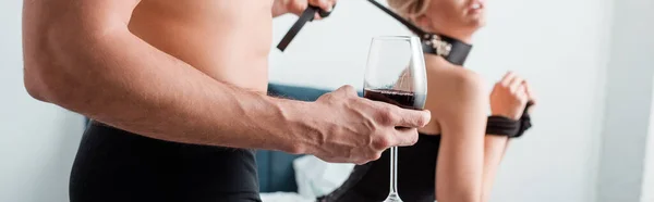Colpo panoramico di donna seducente vicino all'uomo dominante con bicchiere di vino rosso — Foto stock