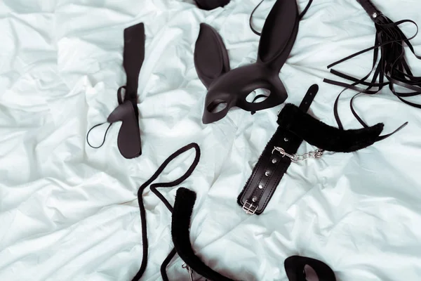 Vista superior de brinquedos pretos para adultos em roupa de cama branca — Fotografia de Stock