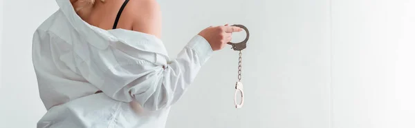 Panoramic shot of young woman in shirt holding handcuffs — Stock Photo