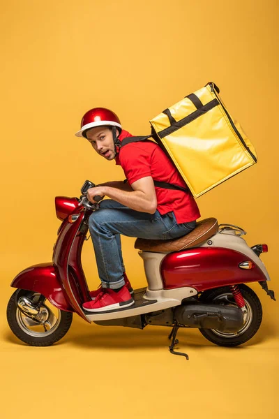 Seitenansicht des Zustellers mit Rucksack auf Roller auf gelbem Hintergrund — Stockfoto