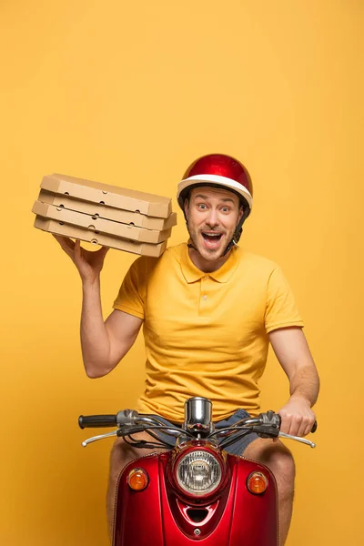 Homem de entrega animado em scooter de equitação uniforme amarelo com caixas de pizza isoladas no amarelo — Fotografia de Stock