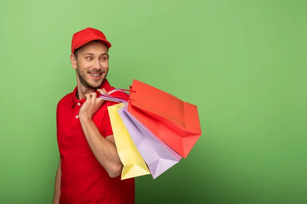 Glücklicher Zusteller in roter Uniform mit grünen Einkaufstüten — Stockfoto