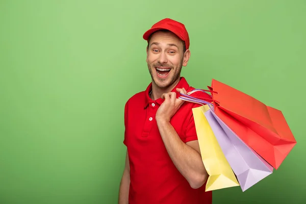 Aufgeregter Zusteller in roter Uniform mit grünen Einkaufstüten — Stockfoto