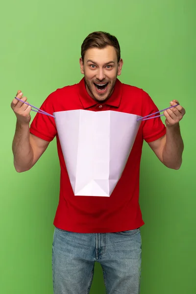 Crazy man holding shopping bag on green — Stock Photo