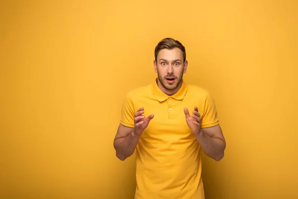 Chocado bonito homem no amarelo roupa gestos no amarelo fundo — Fotografia de Stock