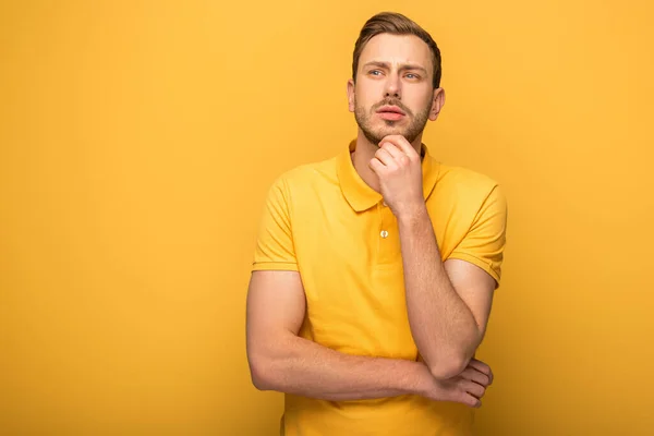 Hombre guapo pensativo en traje amarillo sobre fondo amarillo - foto de stock
