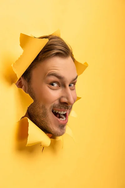 Crazy handsome man with head in yellow paper hole — Stock Photo