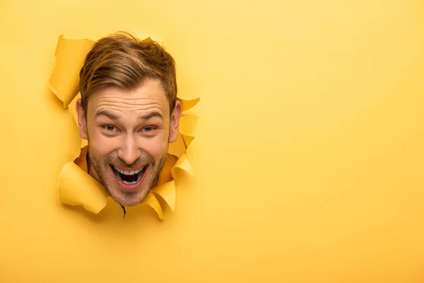 Crazy handsome man with head in yellow paper hole — Stock Photo