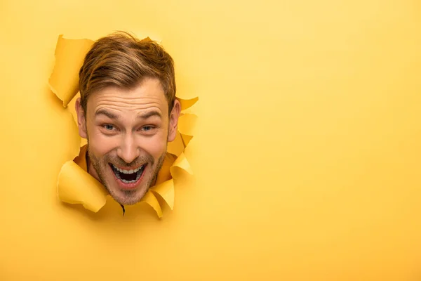 Fou bel homme avec la tête dans le trou de papier jaune — Photo de stock