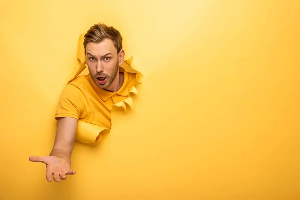 Verwirrter gutaussehender Mann in gelbem Outfit im gelben Papierloch — Stockfoto