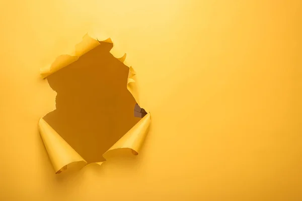 Furo rasgado na textura de papel amarelo com espaço de cópia — Fotografia de Stock