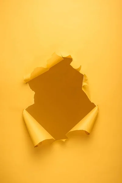 Trou déchiré dans la texture du papier jaune avec espace de copie — Photo de stock