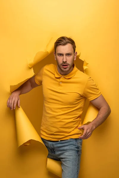 Schöner Mann in gelbem Outfit geht durch gelbes Papierloch — Stockfoto