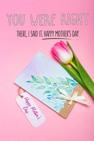 Top view of greeting card with happy mothers day lettering on paper label and tulip on pink background — Stock Photo