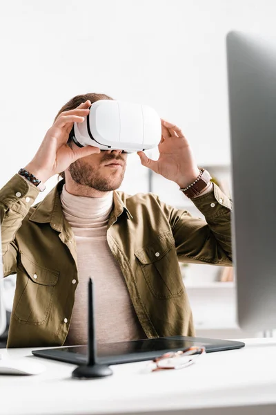 Focus sélectif de l'artiste 3d en utilisant un casque de réalité virtuelle près de la tablette graphique et l'ordinateur sur la table dans le bureau — Photo de stock