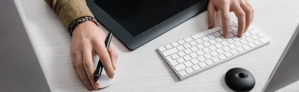 Vista recortada del diseñador digital utilizando el teclado de la computadora y el ratón cerca de la tableta gráfica en la mesa, plano panorámico - foto de stock