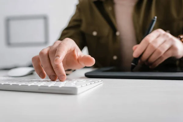 Selective focus of digital designer using computer keyboard and graphics tablet on table — Stock Photo